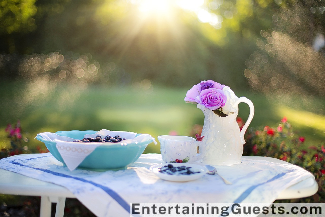 An image of a sunlit table laden with a colorful array of breakfast dishes: fluffy pancakes, fresh berries, sunny-side-up eggs, crispy bacon, and a pitcher of orange juice, amidst a backdrop of morning blooms