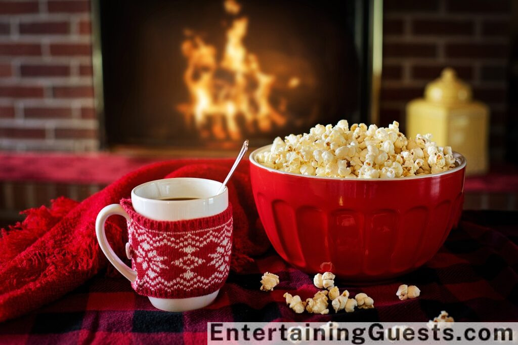 Ate a warm, inviting living room with a fireplace, two people wrapped in blankets on a plush couch, each holding a book, with a steaming mug of hot cocoa on a small table beside them