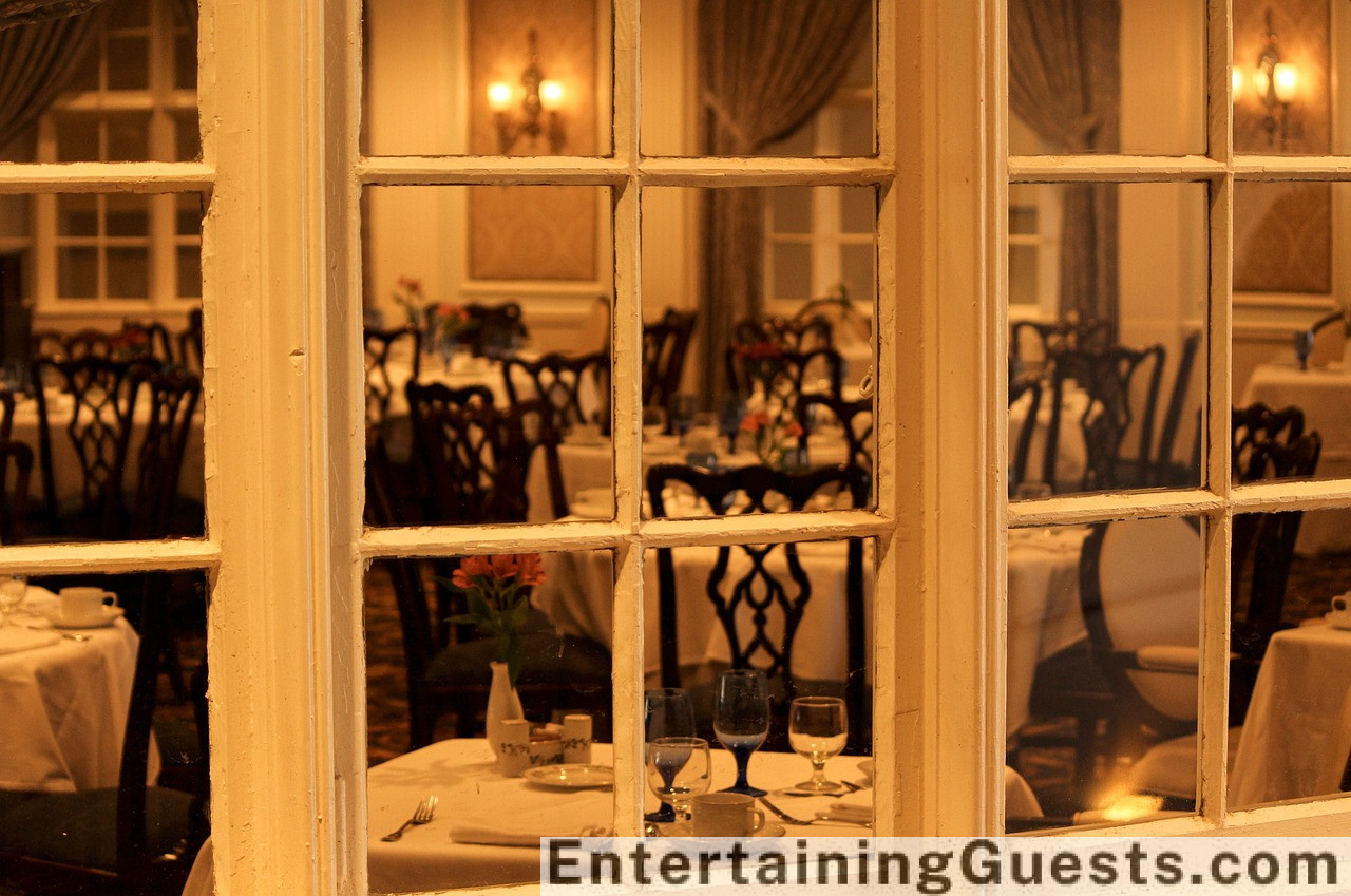 An image of an elegant dining table in a cozy restaurant, showcasing a variety of gourmet dishes, sparkling drinks, and a centerpiece of flowers, with soft lighting and happy diners in the background