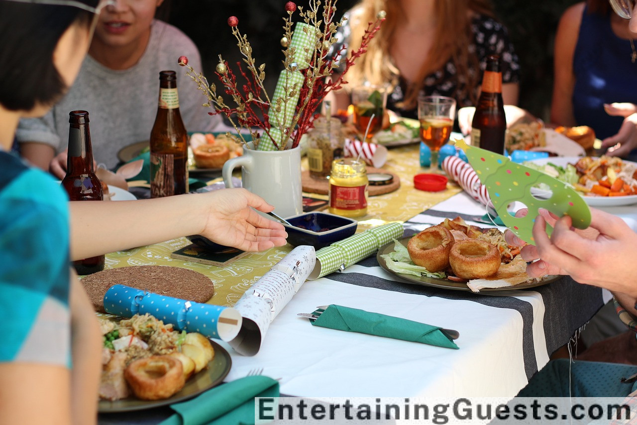 An elegant table setting with a variety of unique dinnerware, a decanter with glasses, a gourmet cheese platter, and exotic spice jars, all surrounded by soft candlelight