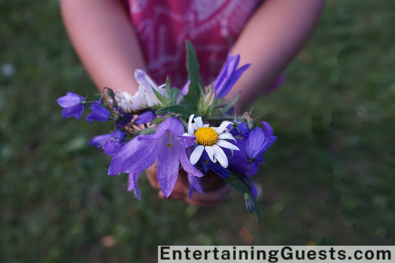 Ate a lively wedding scene featuring guests of all ages enjoying a photo booth, a dance floor with a live band, and an outdoor area with lawn games under string lights at sunset