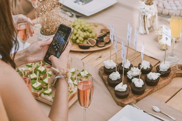 Woman taking a photo of cupcakes placed on a wooden board.